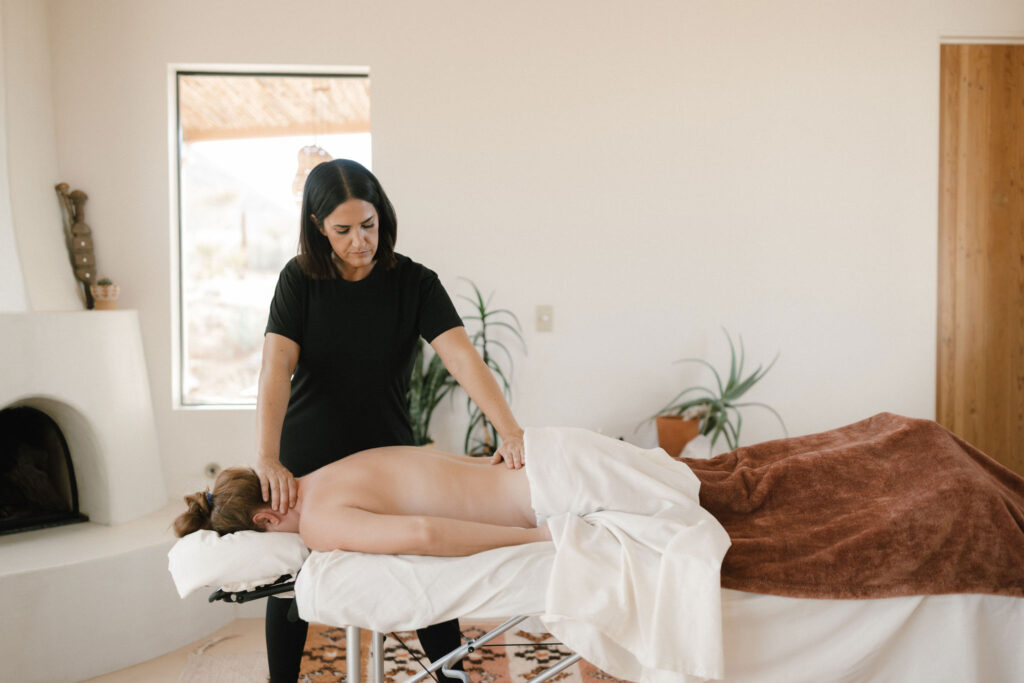 Massage therapist providing back and neck massage in a calm home environment.