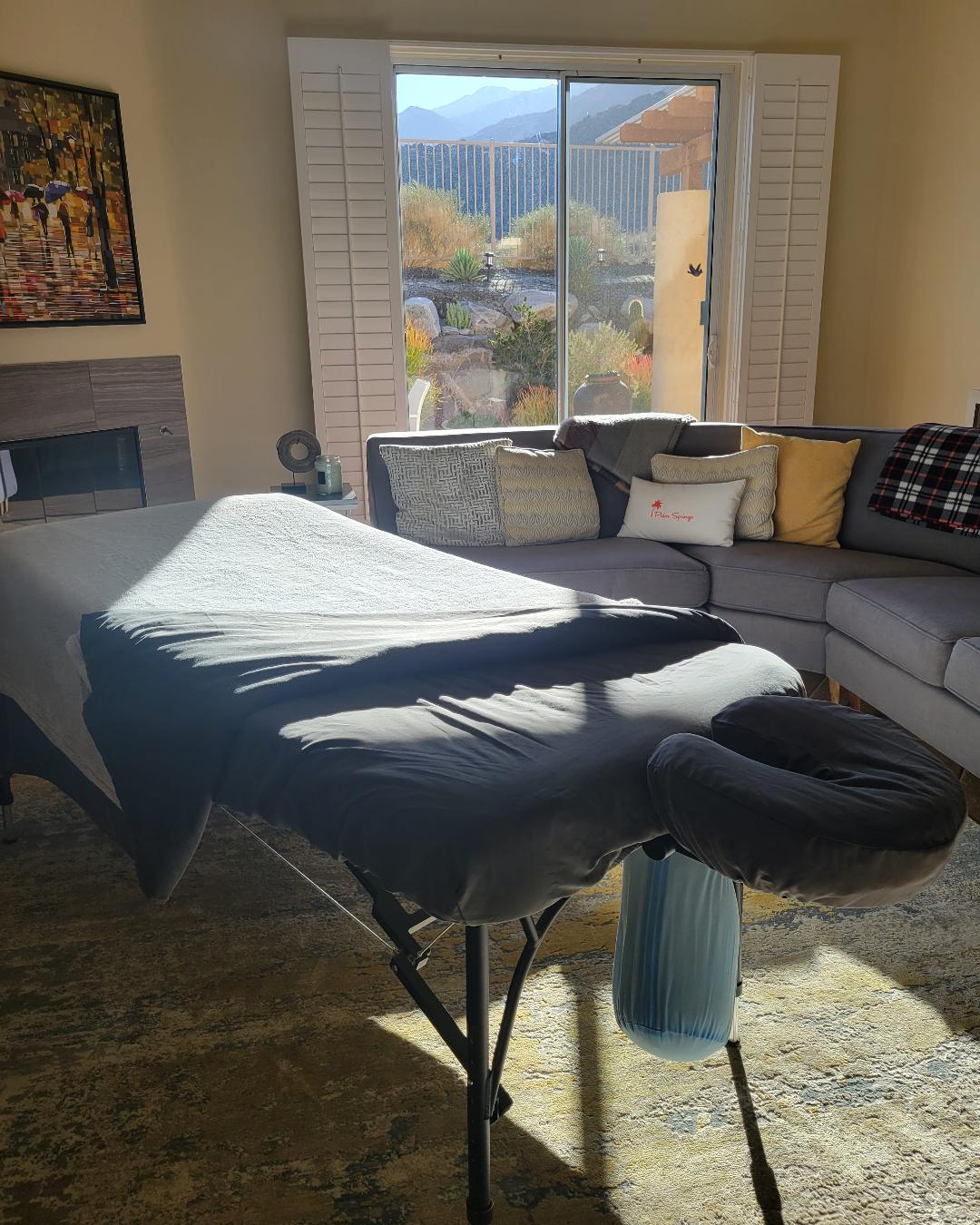 Massage table arranged in a bright, stylish living room for an in-home session.